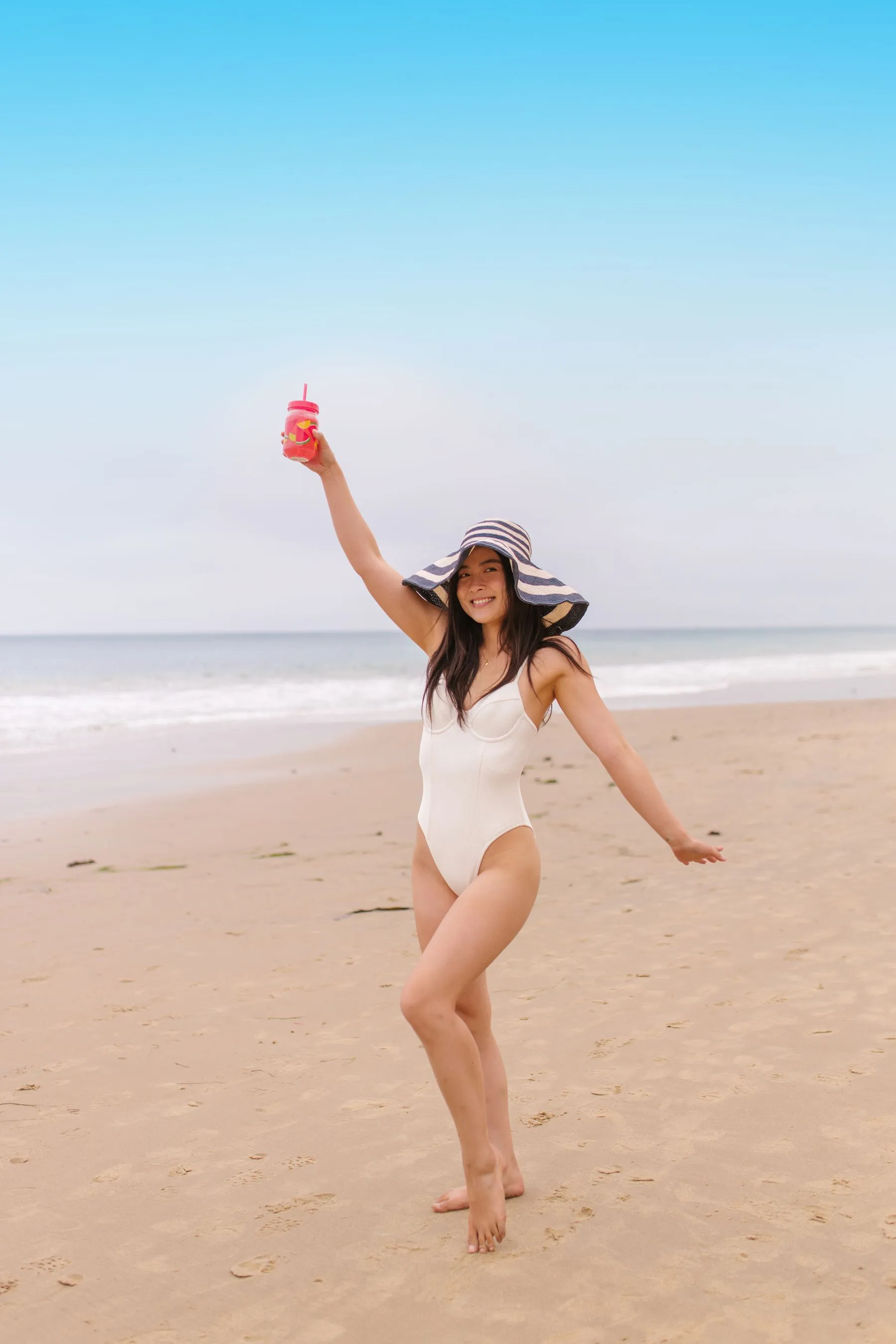 Femme en maillot une-pièce blanc marchant sur une plage