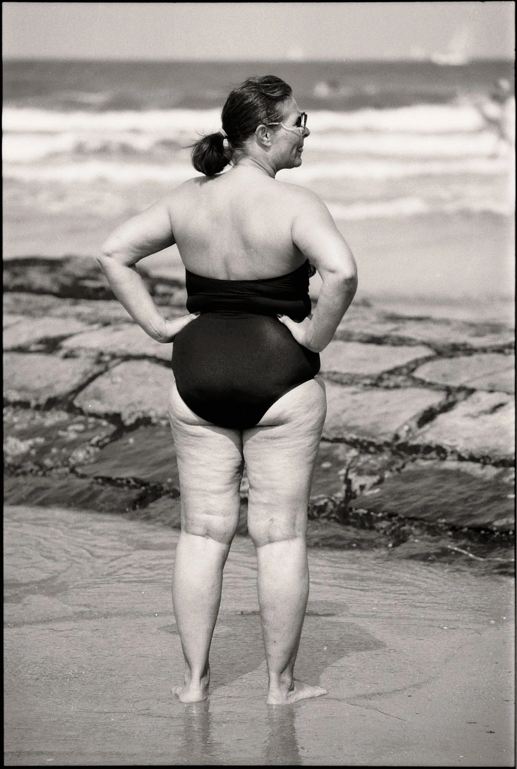 Femme grande taille portant un maillot une-pièce noir à la plage